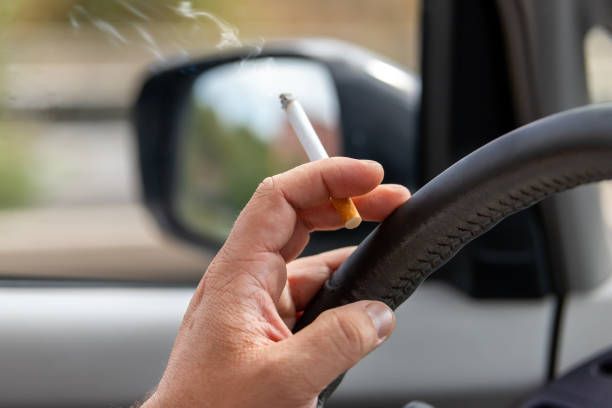 smoking in a car, a cigarette in hand